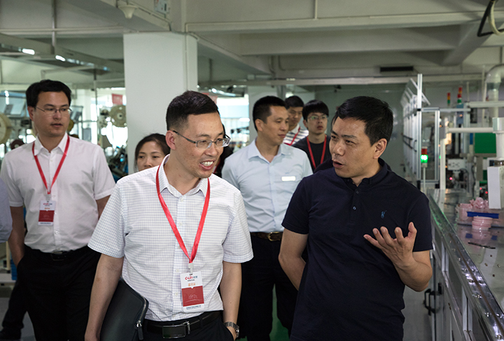 欣靈公司總裁張彭春（右一）陪同市委領導參觀車間